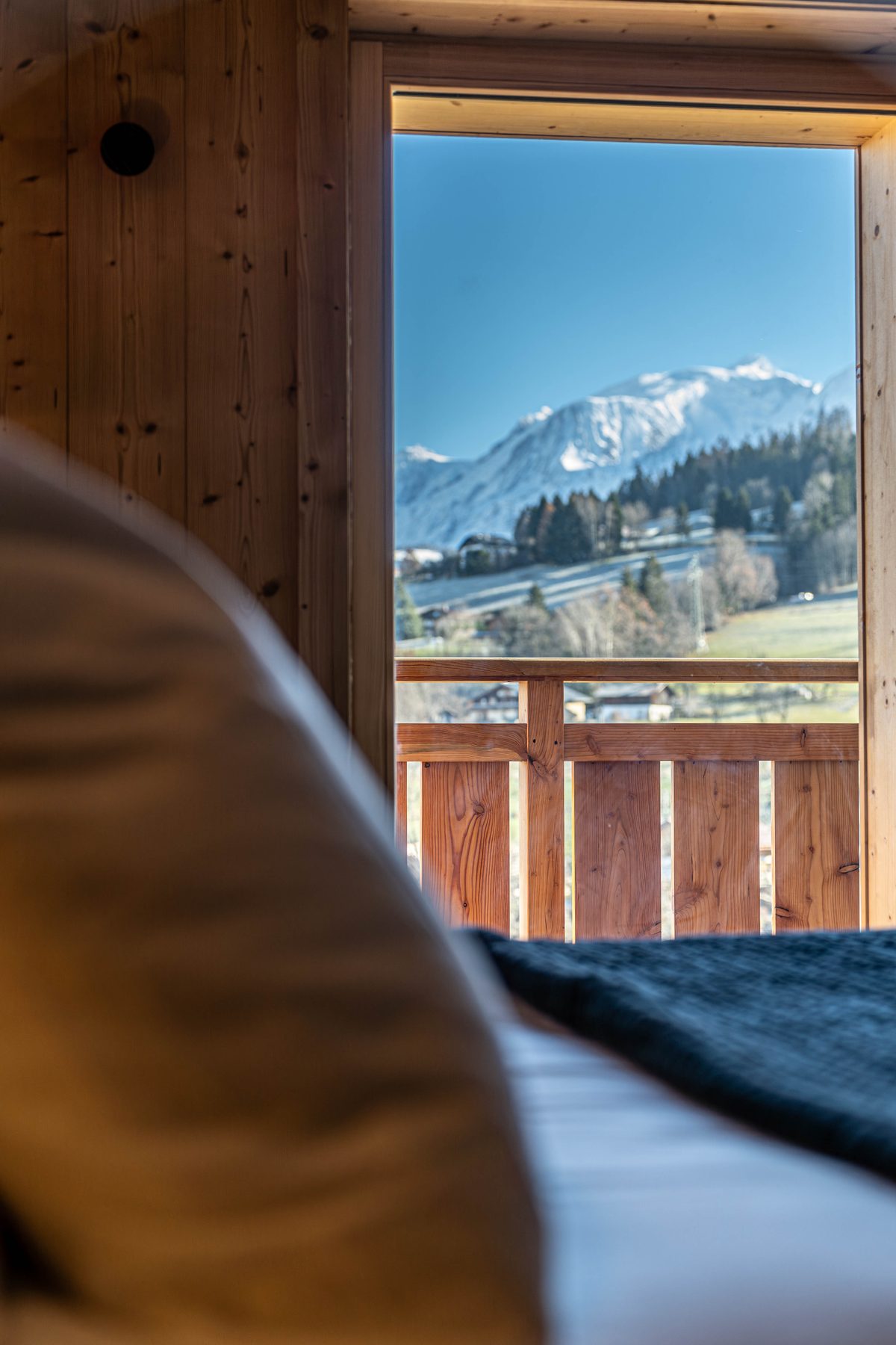 Vue sur le massif du Mont-Blanc depuis une chambre, lit au premier plan
