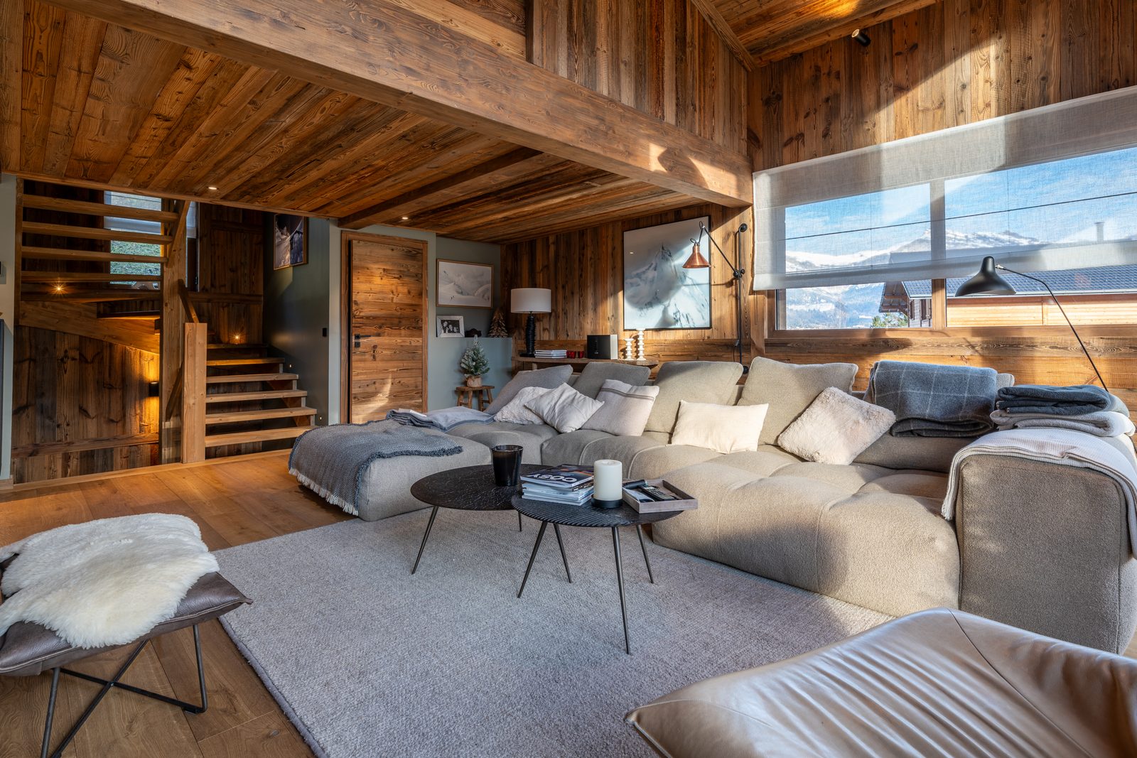 Salon d'un chalet en bois avec grand canapé et vue sur les montagnes
